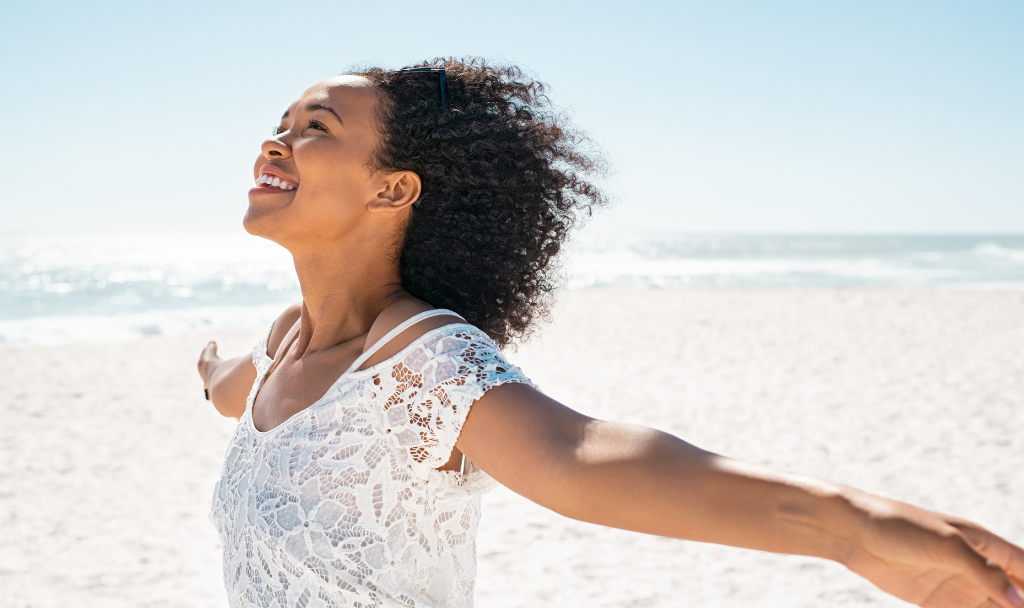 Embracing Change. Image of a woman with her arms widespread as she smiles while standing outside.