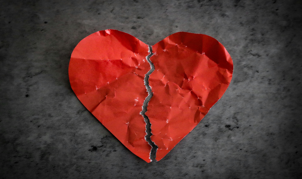 Navigating the Stages of Grief Post-Breakup. Image of a crumpled paper heart torn into two pieces.