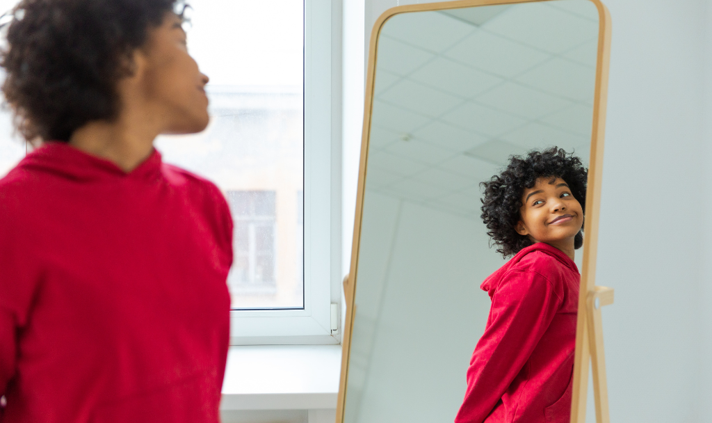 Perfectionism and Self-Acceptance: Embracing Imperfection as a Strength. Image of a woman looking at herself in a mirror.